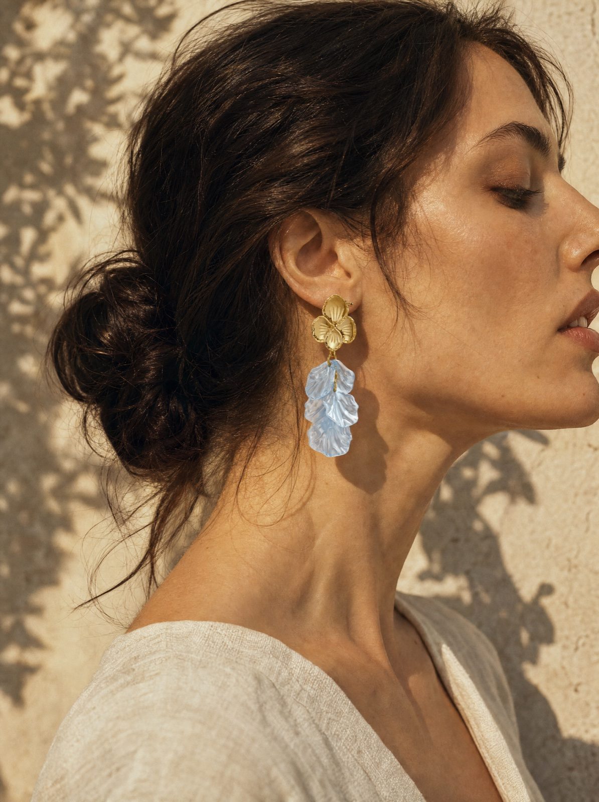 woman wearing the flower earrings in mother of pearl, baby blue, side profile in soft afternoon light