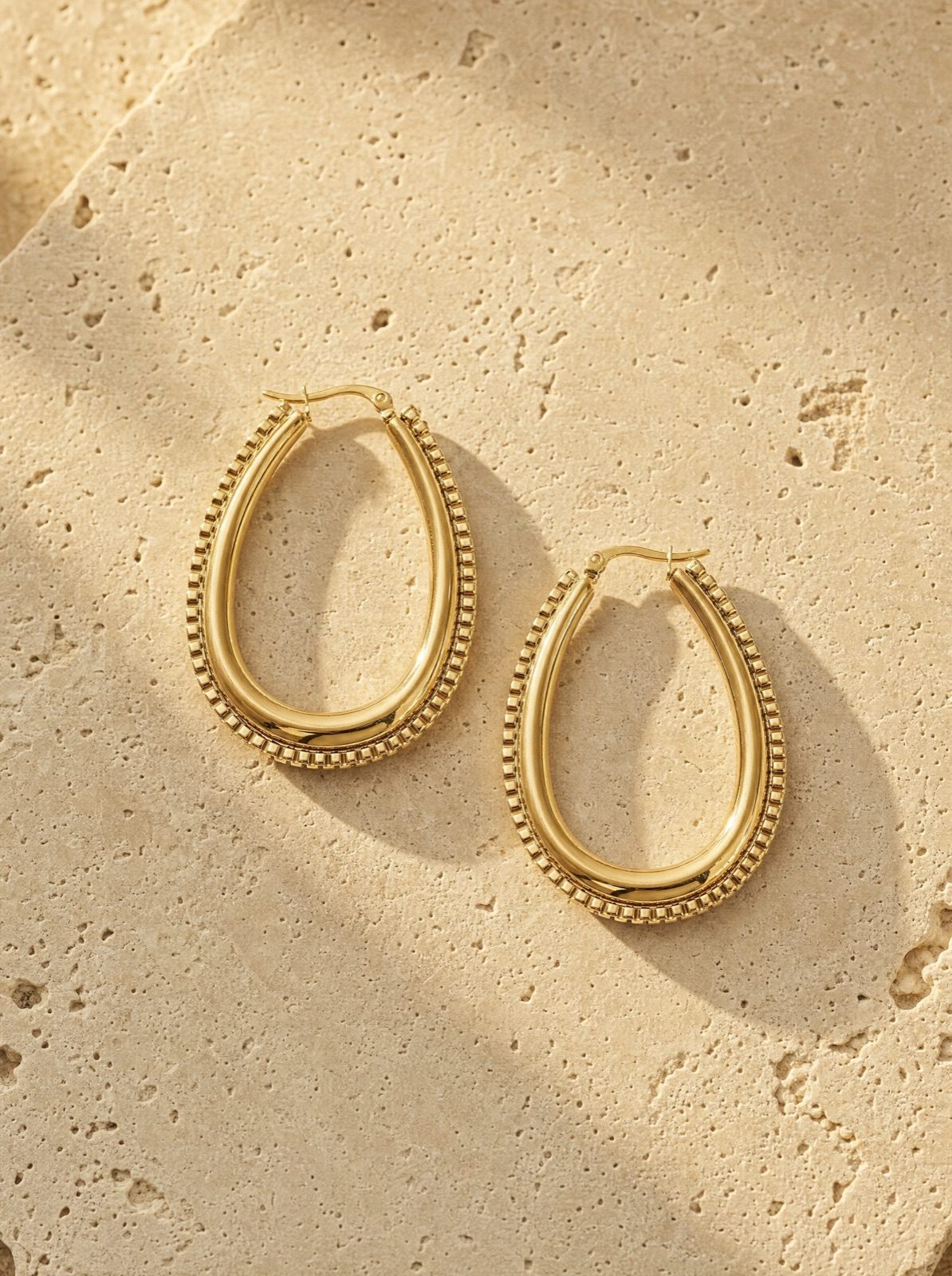 link drop earrings in gold stainless steel on travertine stone in afternoon light