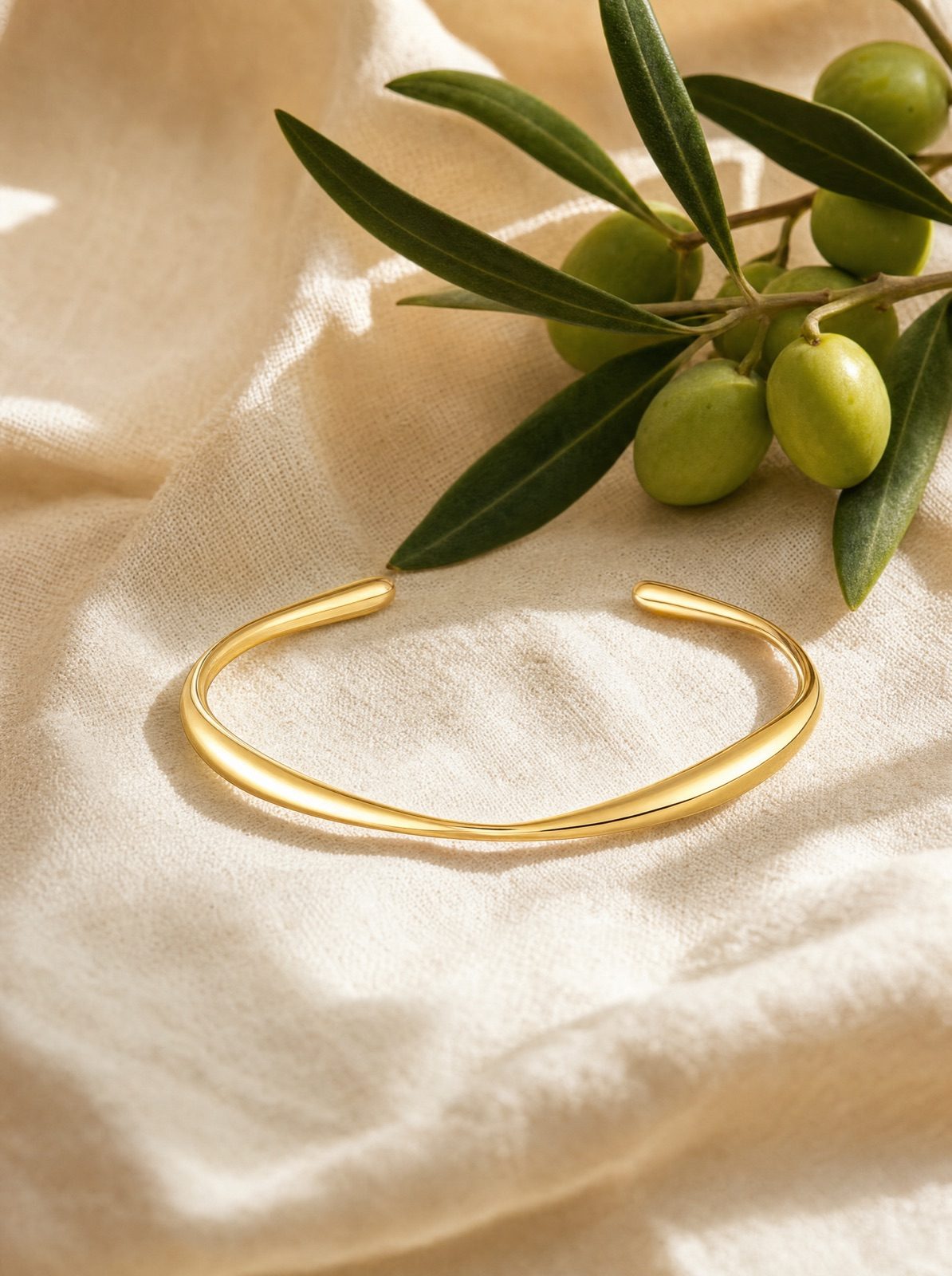 organic cuff in gold on cream linen with an olive branch
