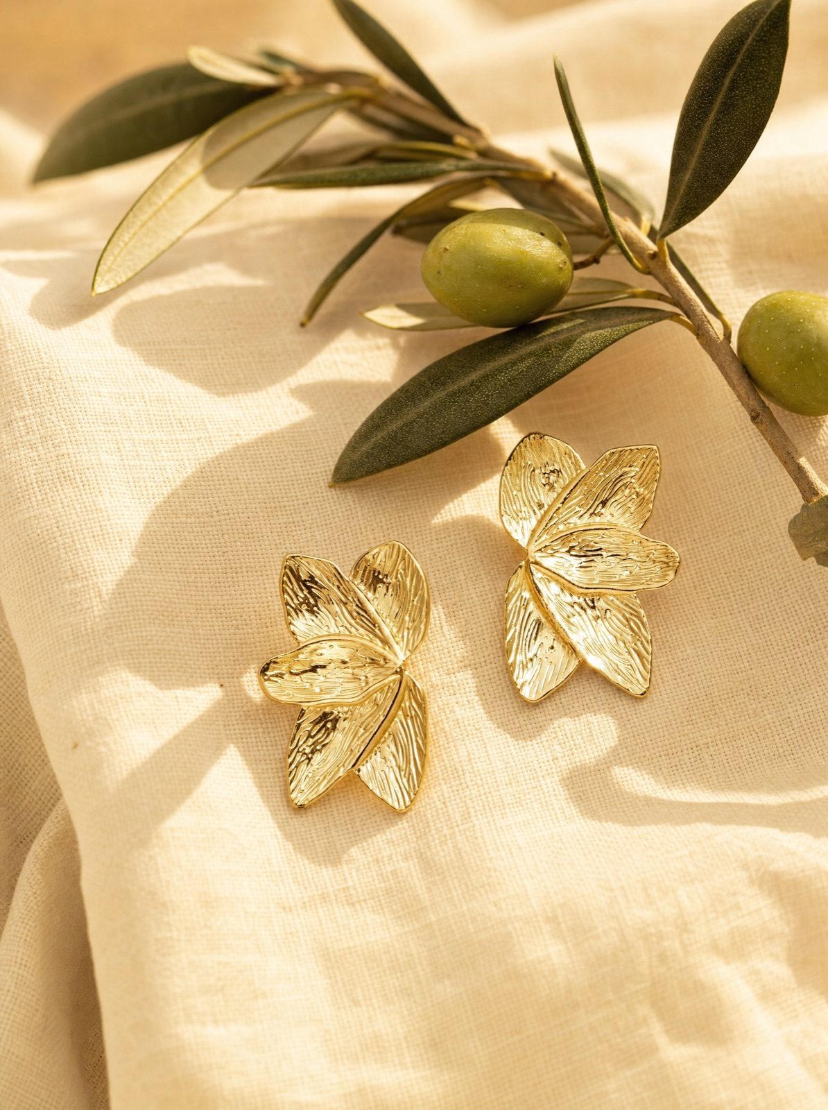 leaf studs in gold on cream linen with an olive branch