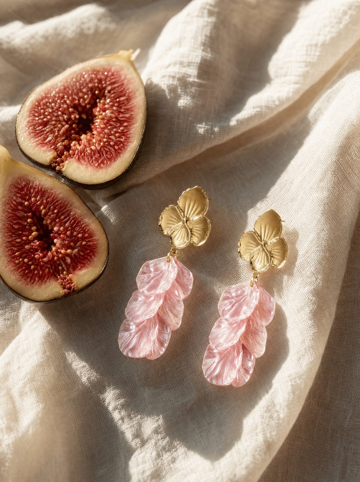 flower earrings in mother of pearl, light pink, on folded cream linen with halved figs