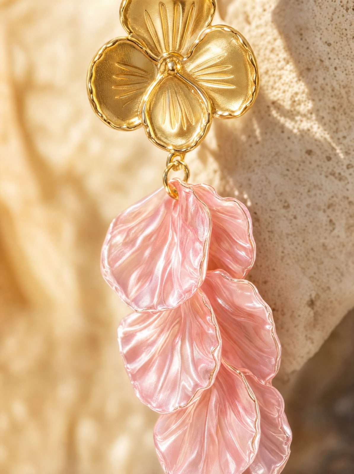 macro detail of a single flower earring in mother of pearl, light pink, on travertine stone