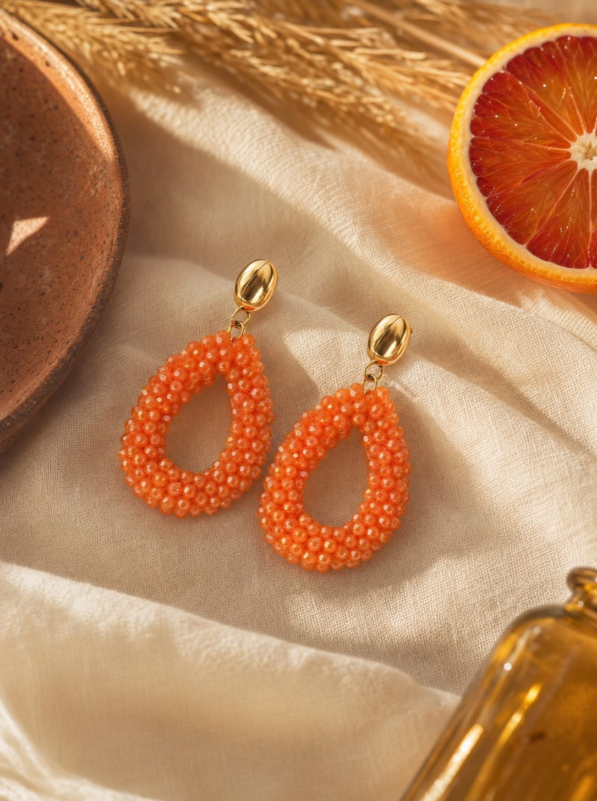 amalfi drops in orange on cream linen with a halved blood orange and wheat