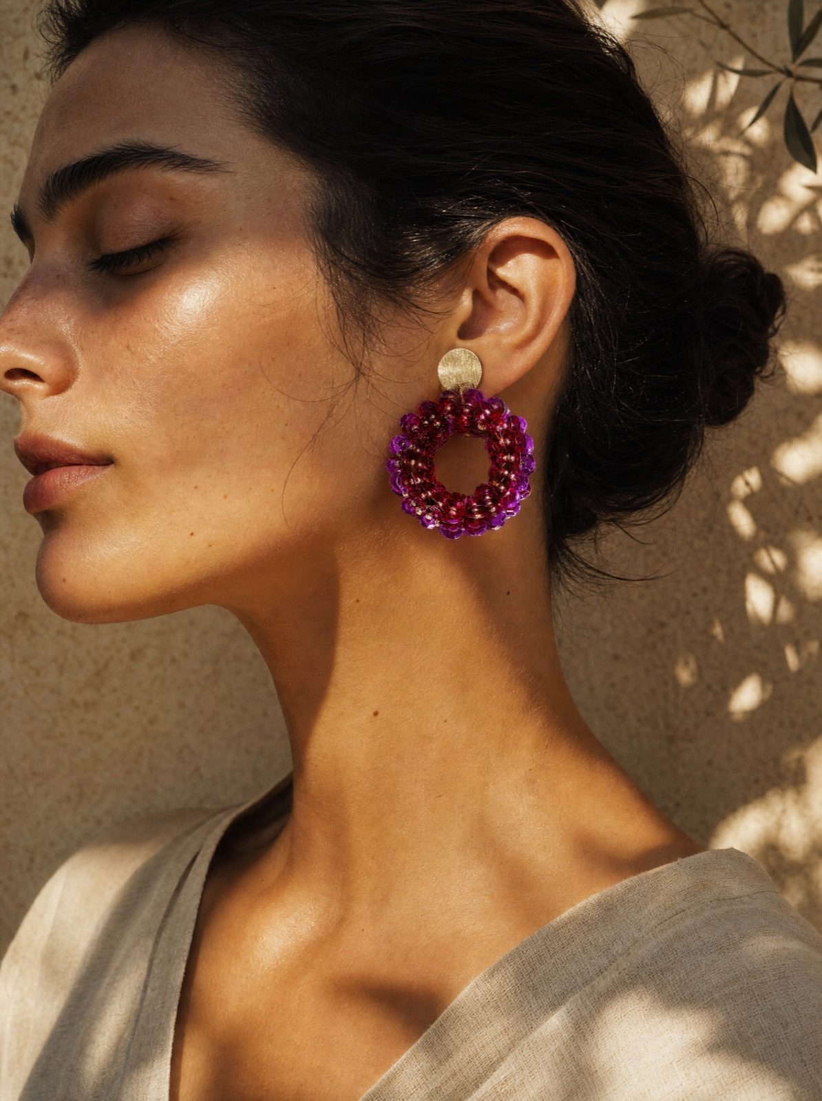 close-up profile of woman wearing the purple sequin drop earrings, eyes closed in soft light