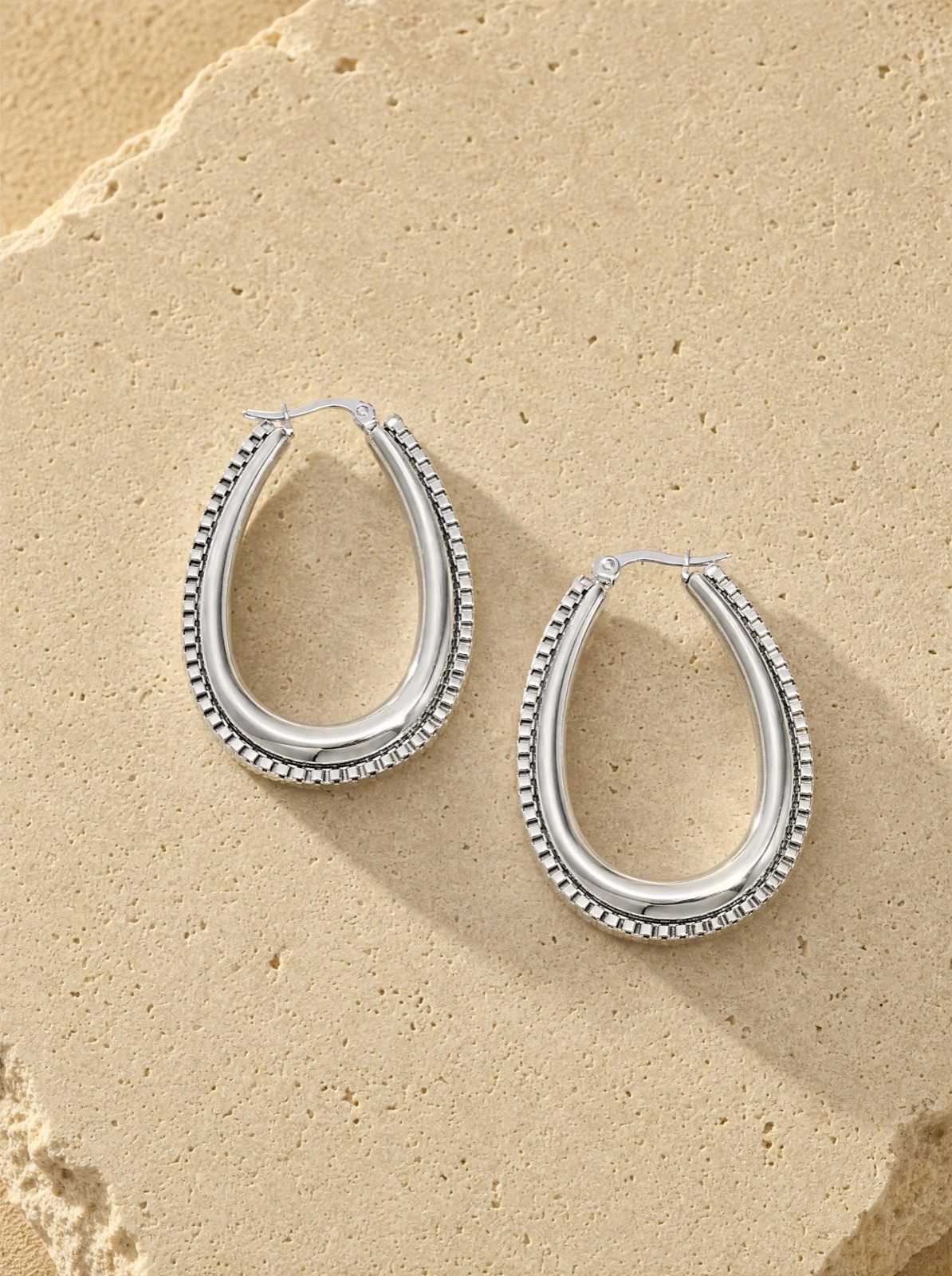 link drop earrings in silver stainless steel on travertine stone in afternoon light