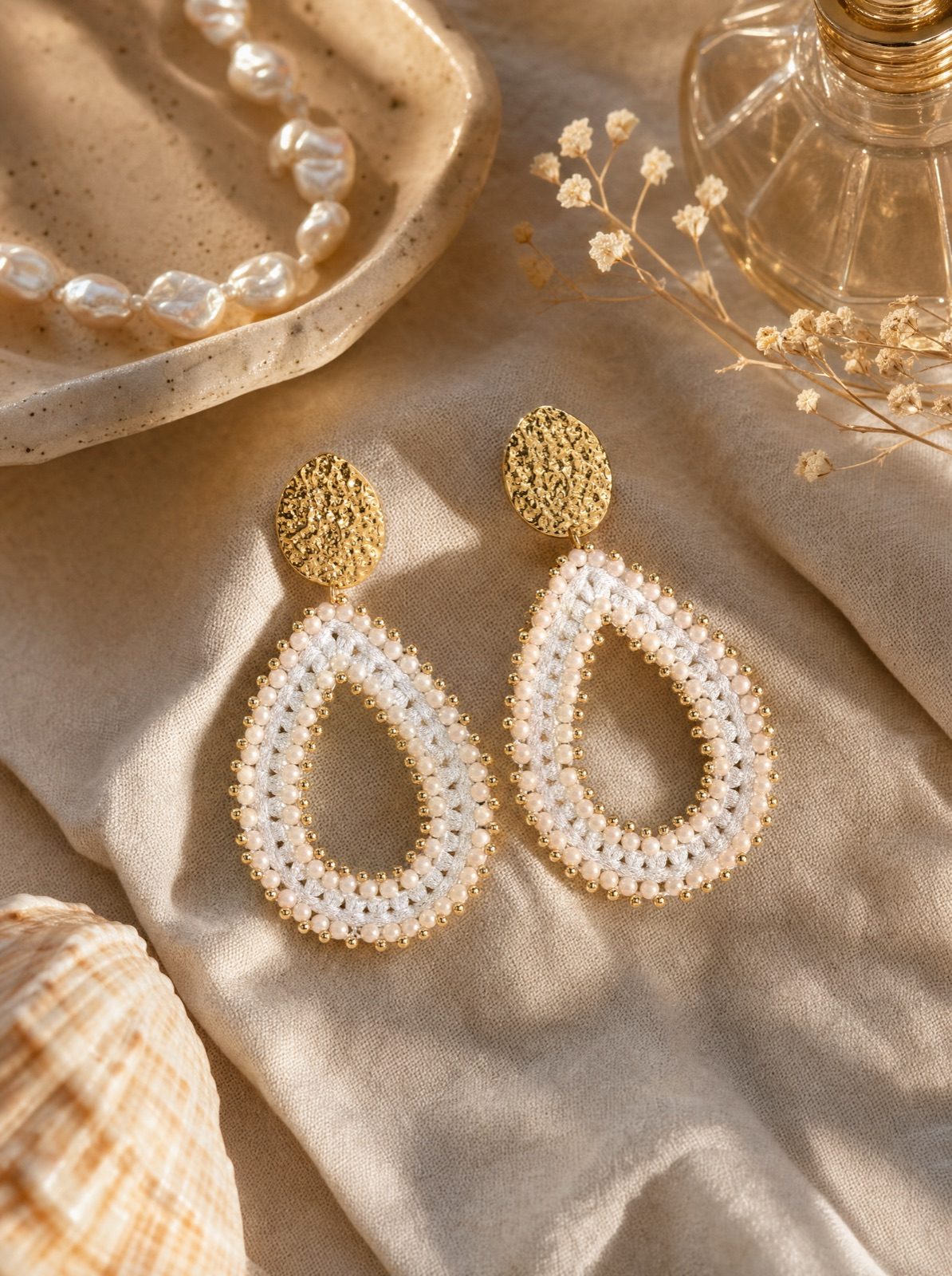 riviera drops in pearl white on cream linen with pearls and a ceramic vessel